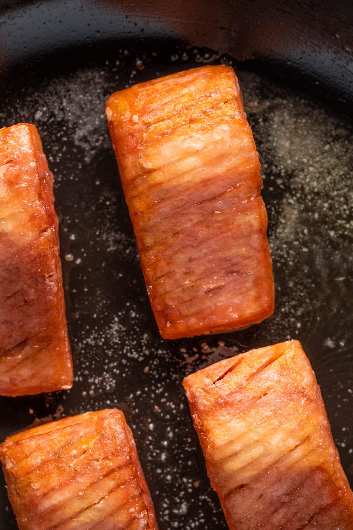 Fried vegan salmon pieces in a frying pan.