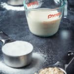 Flour, soy milk, sugar and oats in measuring cups.