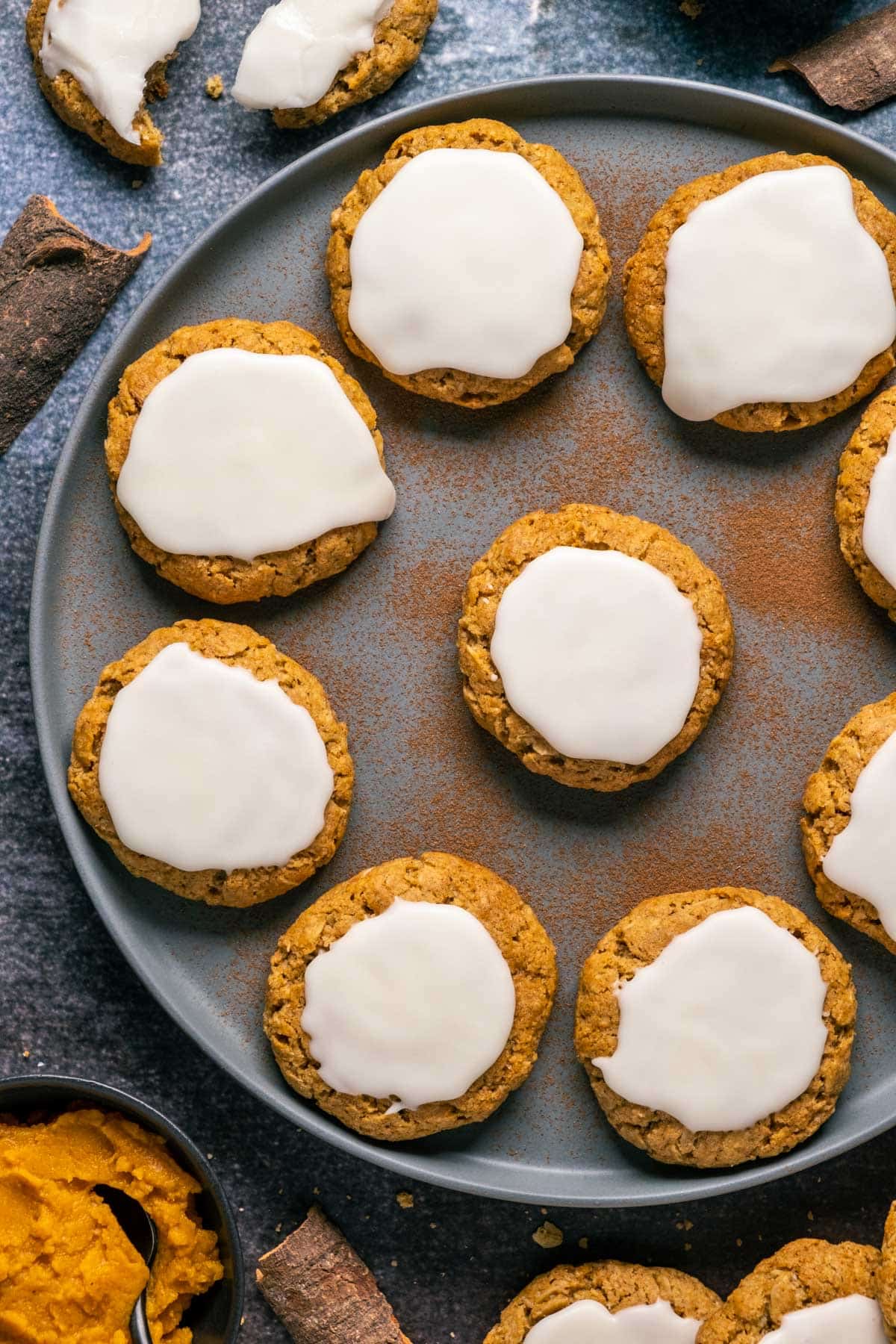 Frosted pumpkin oatmeal cookies on a gray plate.