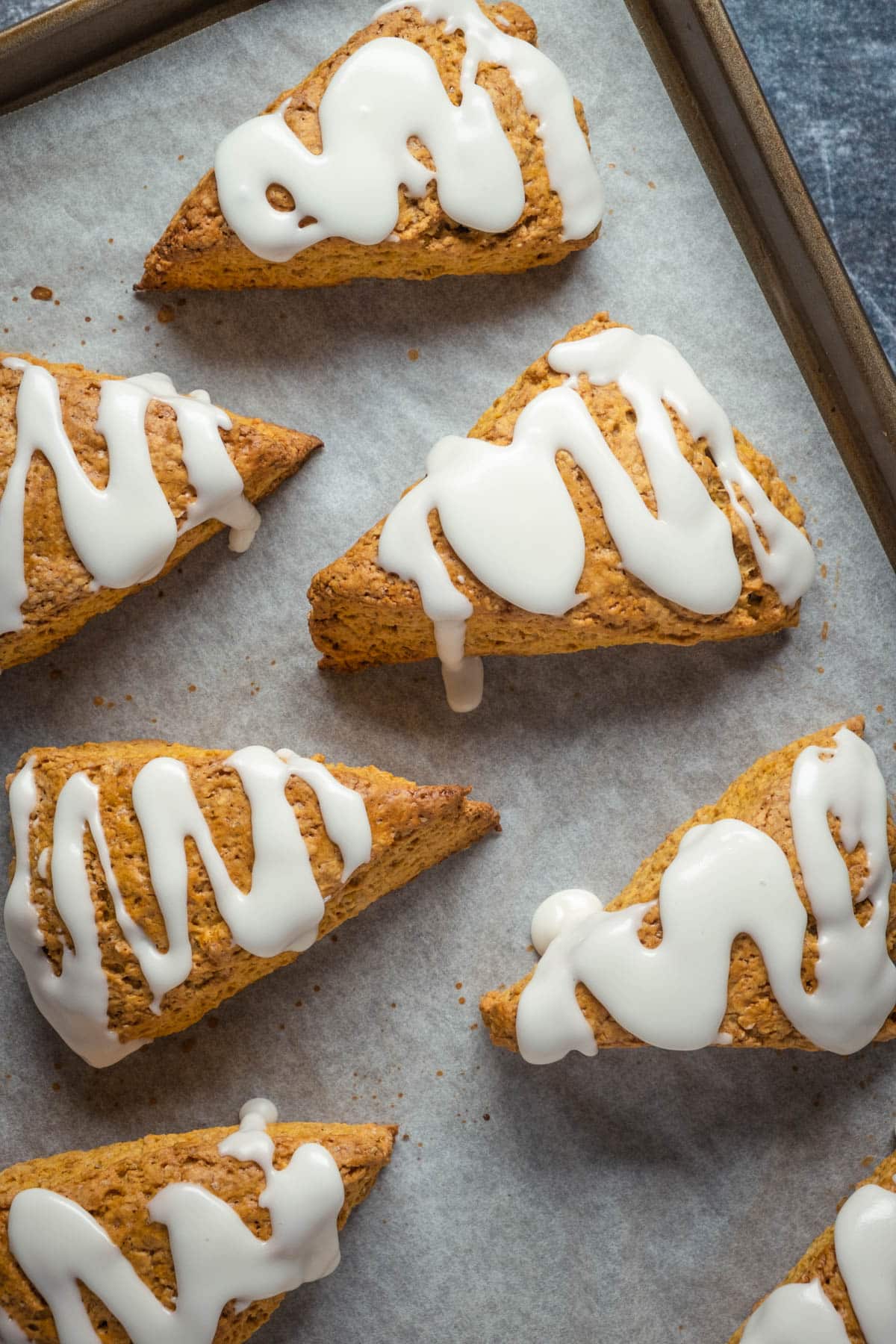 Pumpkin scones on a parchment lined baking sheet.