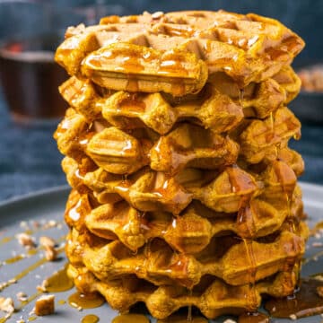 Vegan pumpkin waffles stacked up on a plate.