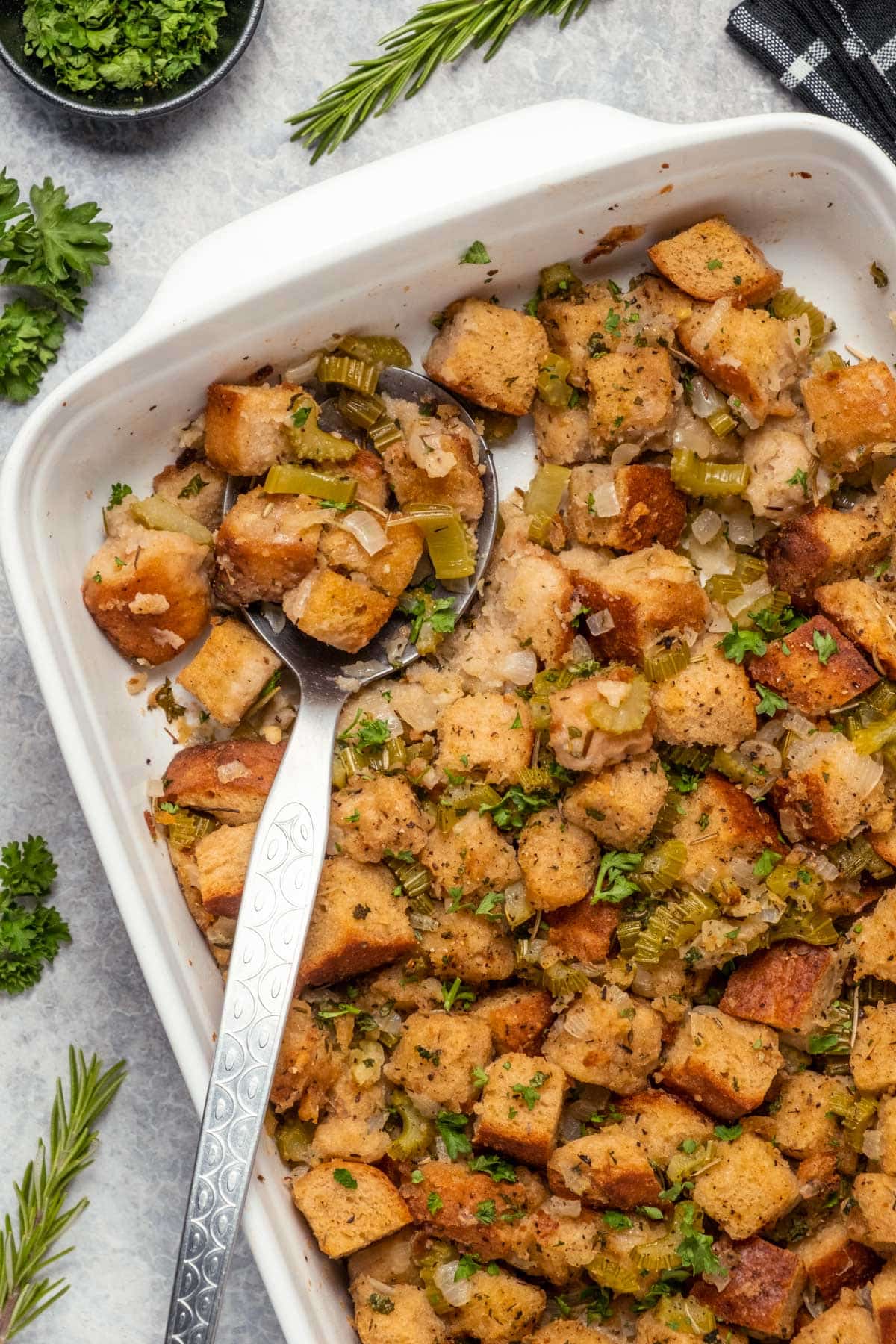 Vegan stuffing in a white dish with a serving spoon.