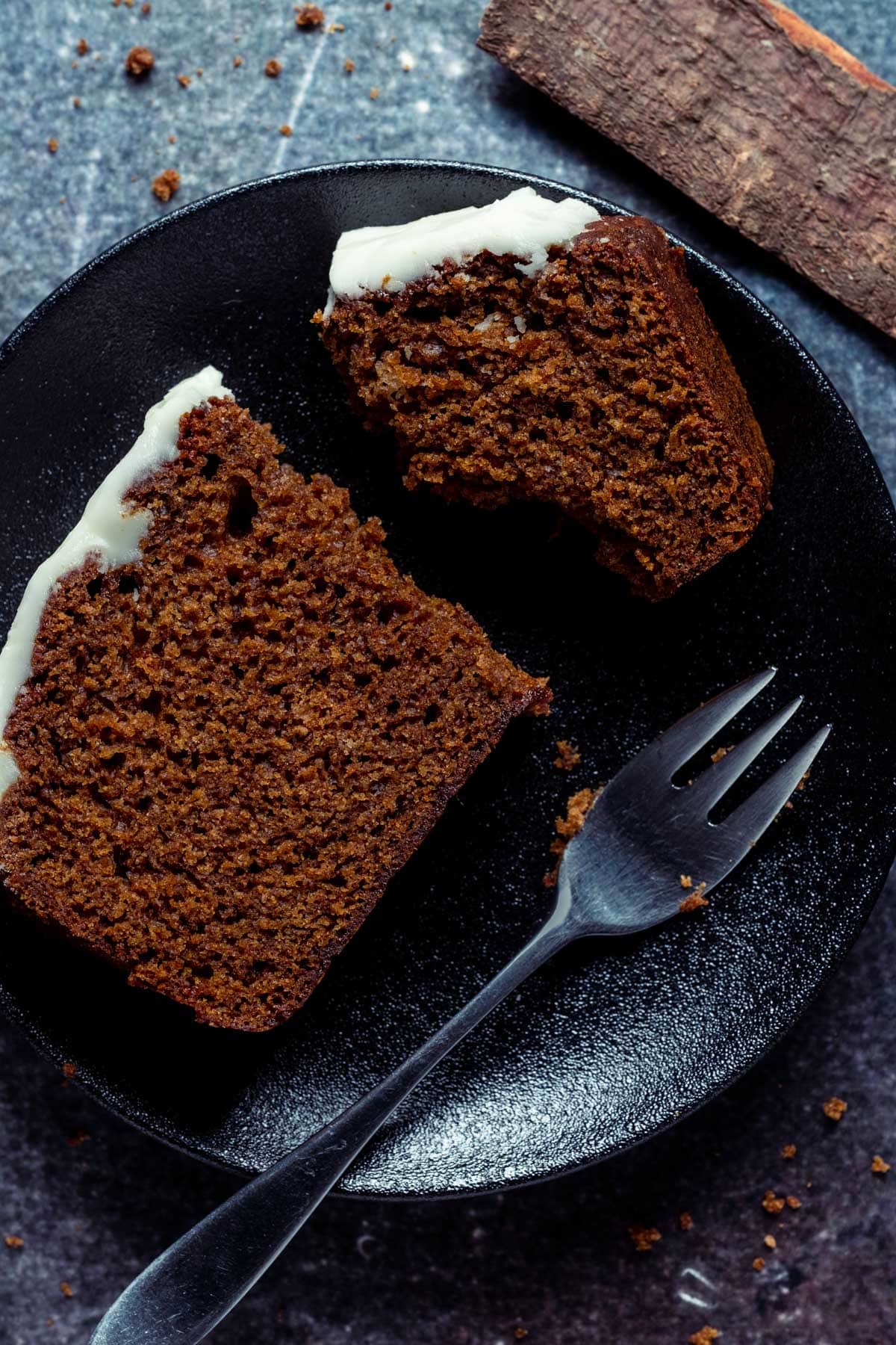 Lebkuchenscheibe auf einem schwarzen Teller mit einer Kuchengabel.