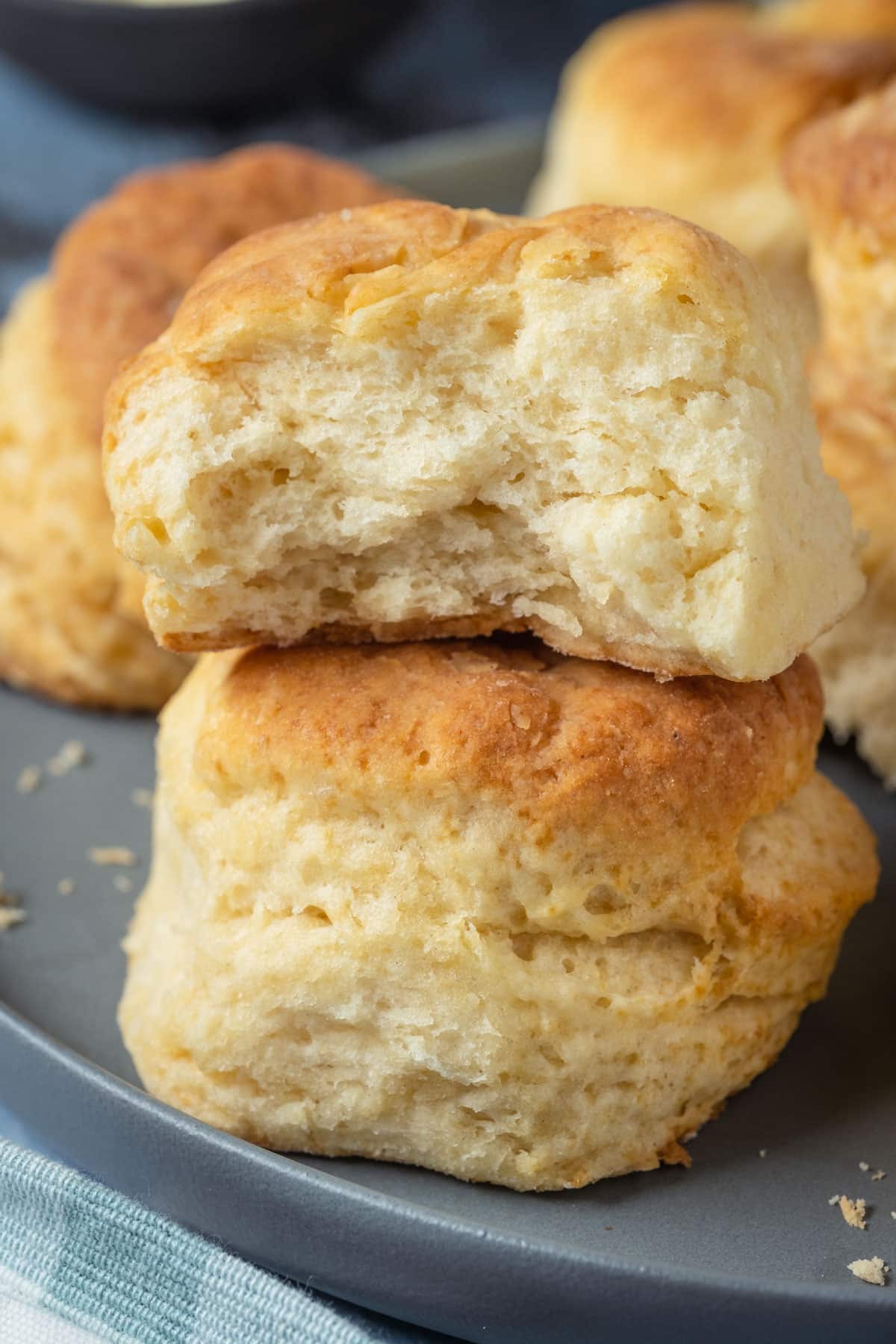 One golden buttermilk biscuit cut in half, stacked on top of another on a grey plate 