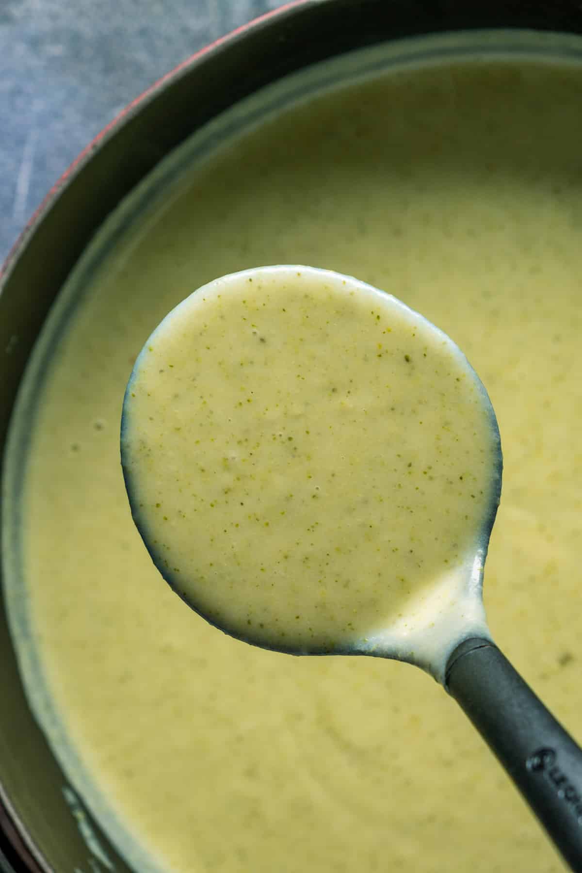 Vegan potato broccoli soup served in a ladle.